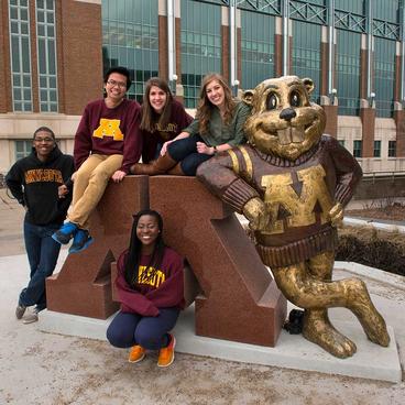 students posing for photo next to the Goldy statue